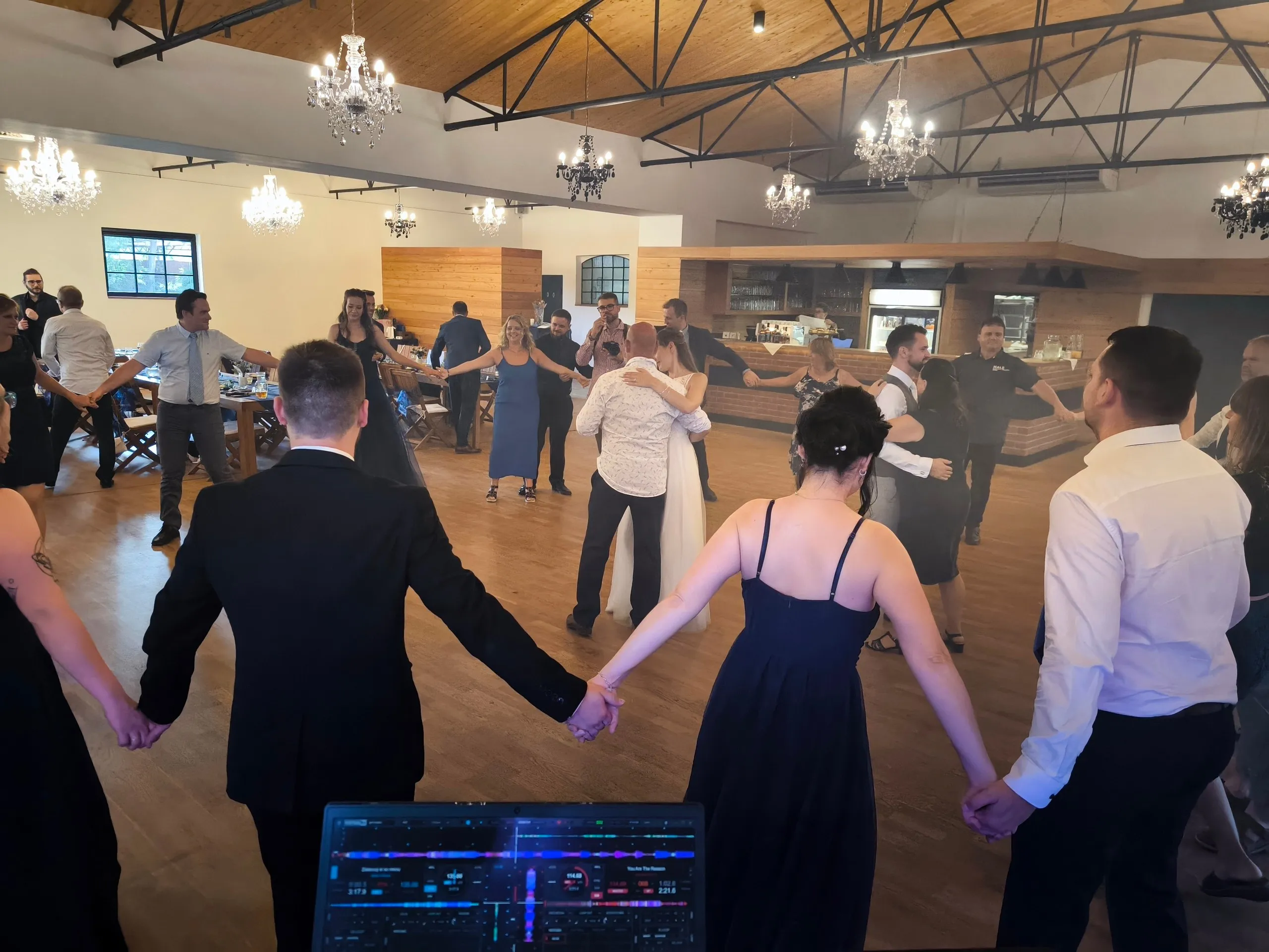 Kolo tančících hostů pohledem od DJ pultu